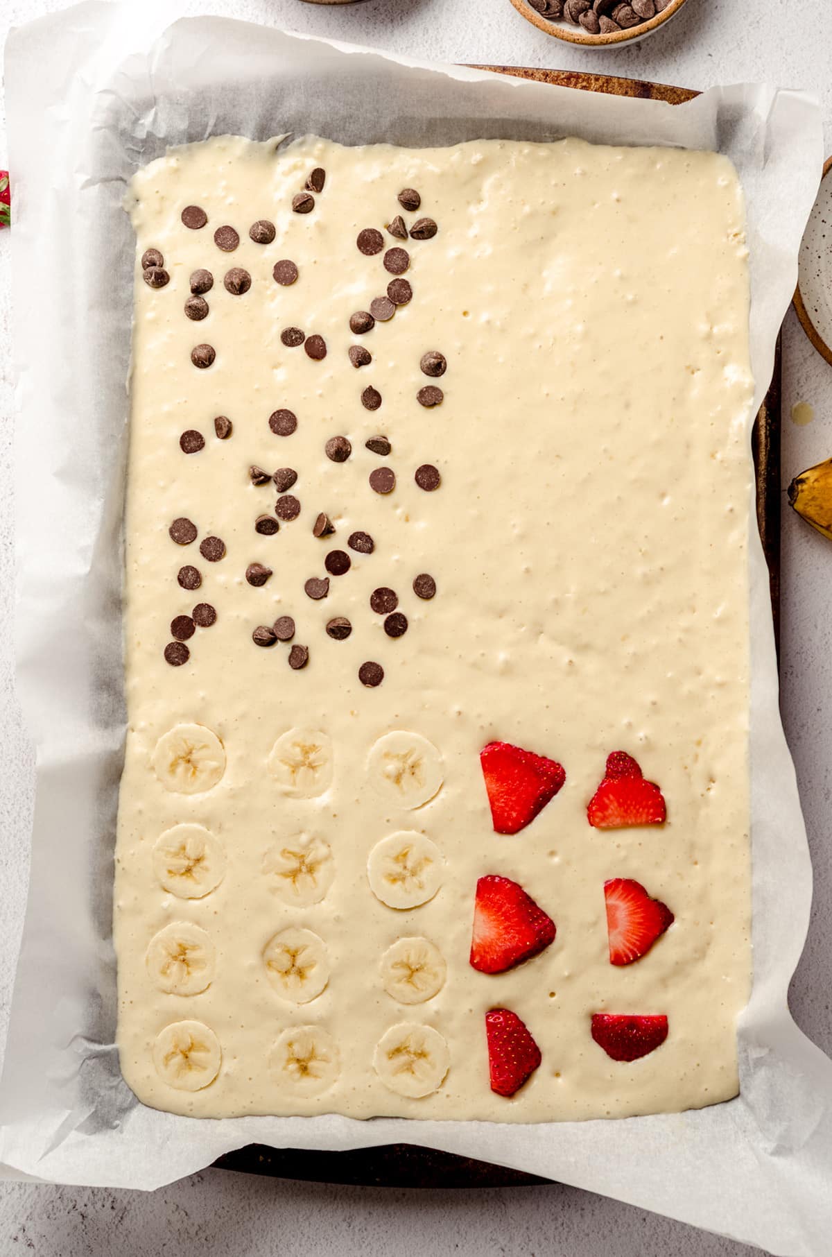 aerial photo of sheet pan pancake batter and toppings in a large baking sheet