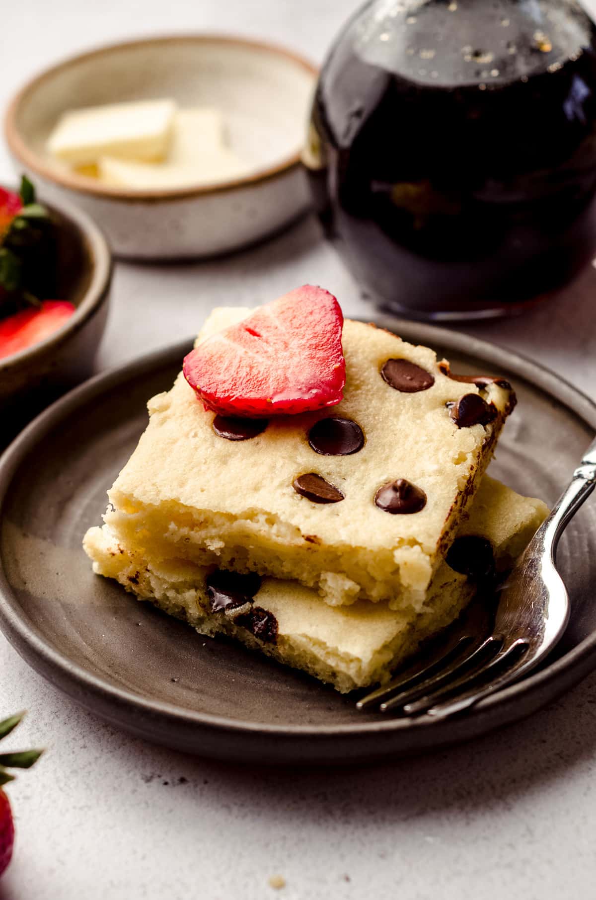 stack of chocolate chip sheet pan pancakes with a strawberry slice on top