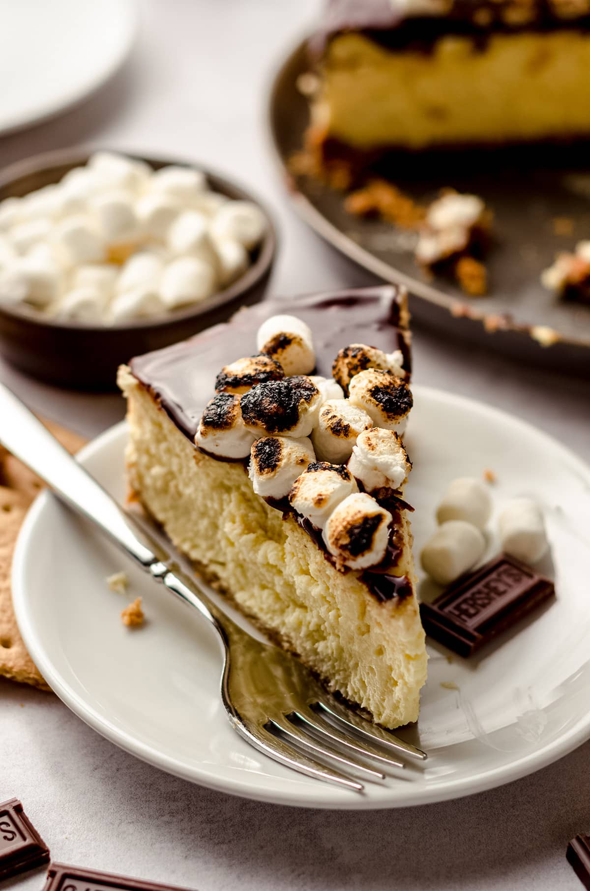 A slice of S'mores cheesecake with marshmallows on top.