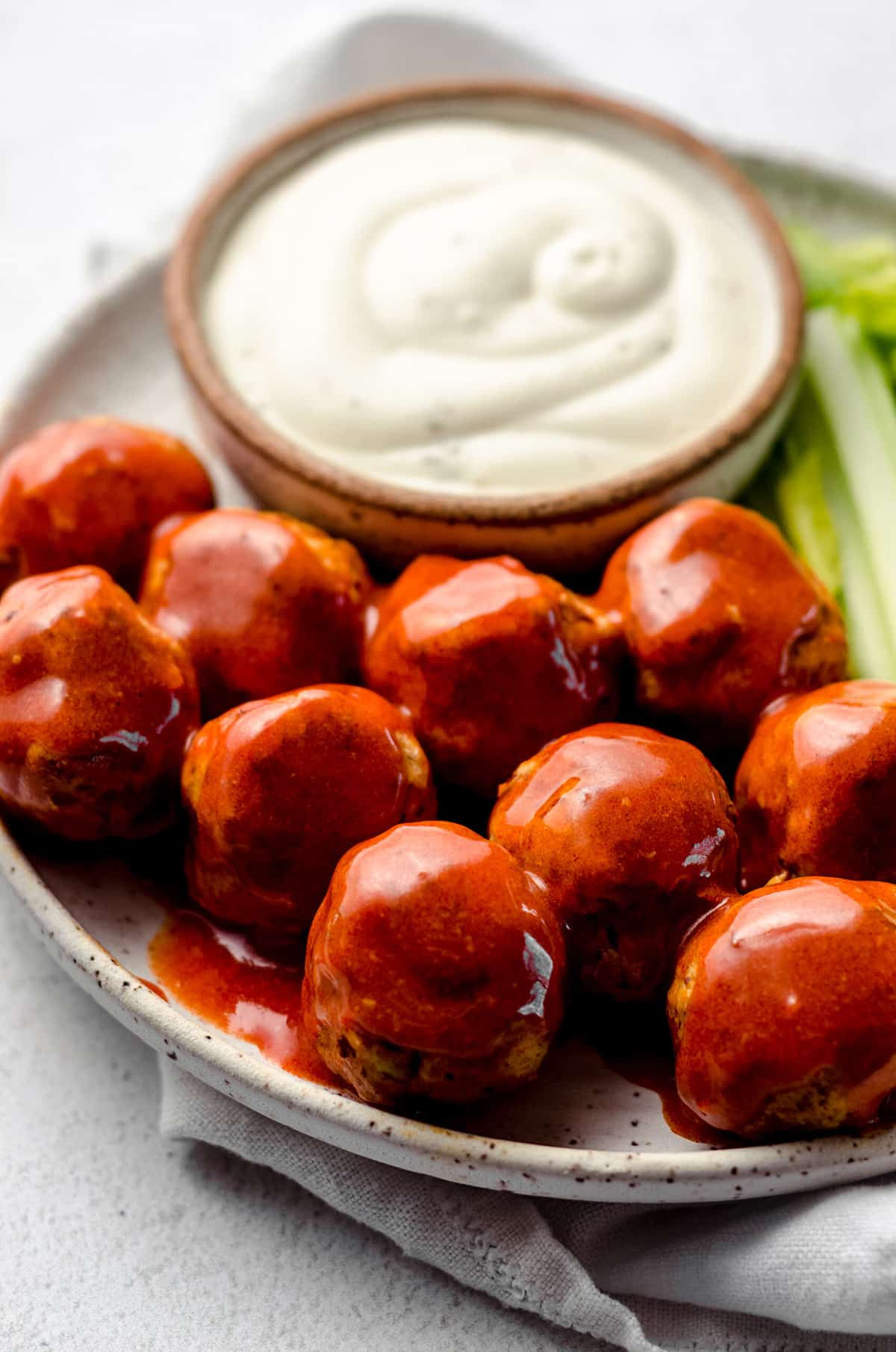 A plate of meatballs with a creamy sauce on the side.