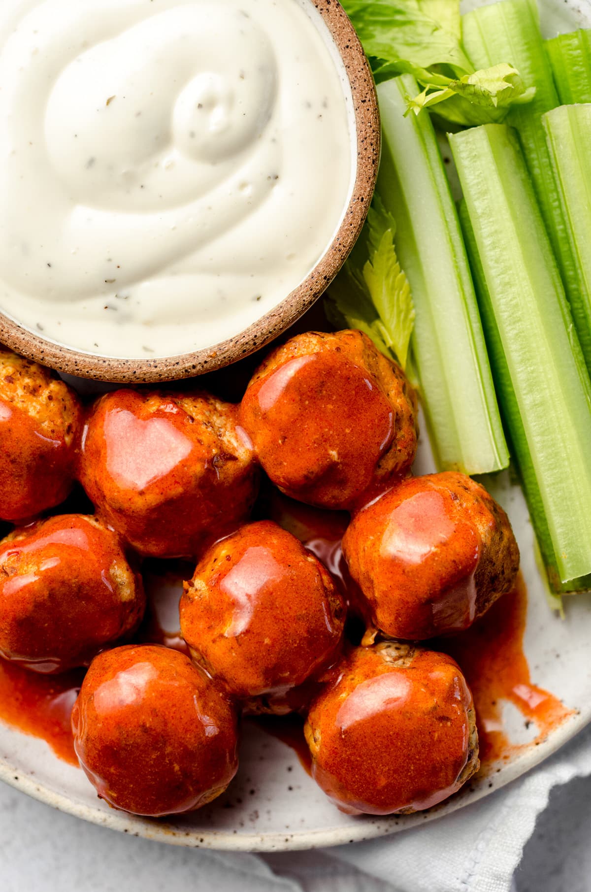 A plate of chicken meatballs coated in buffalo sauce.