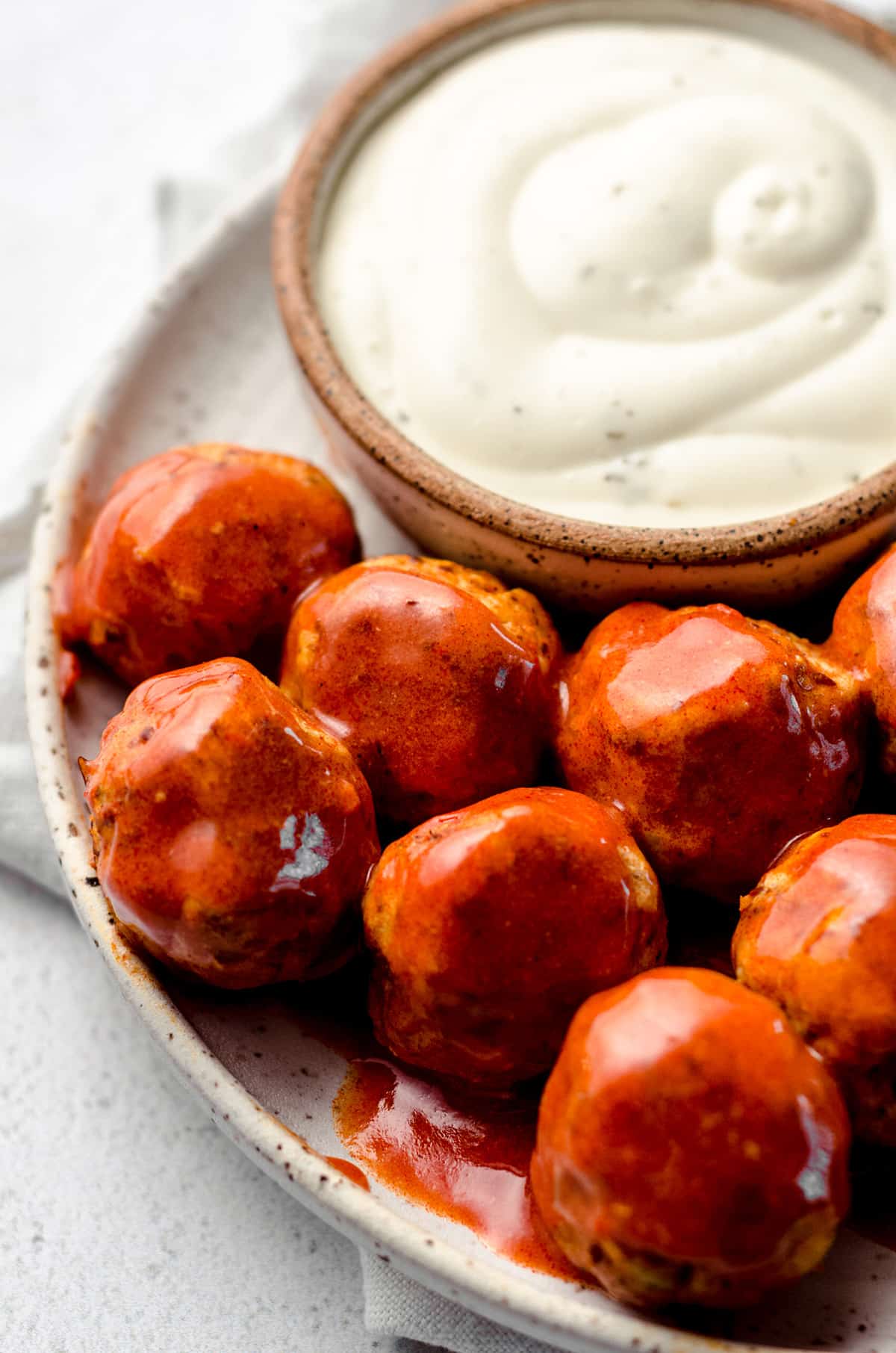 A plate filled with buffalo sauce covered meatballs.