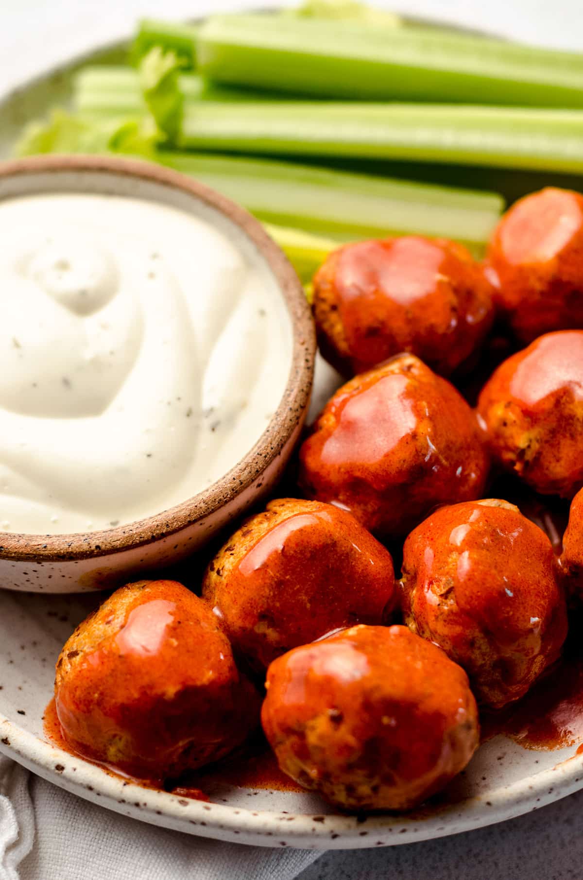 A plate filled with meatballs, celery and creamy dressing.