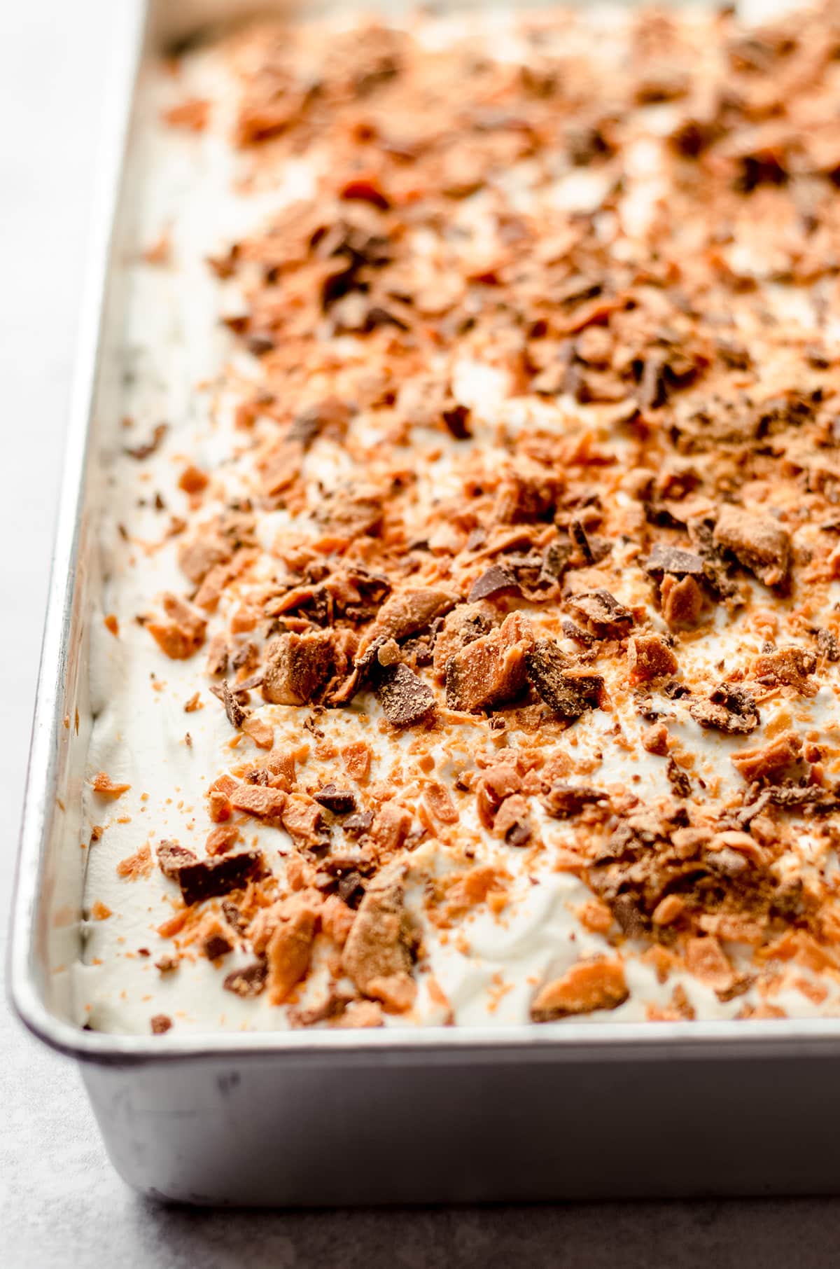 A rectangular cake pan covered in crushed butterfingers.
