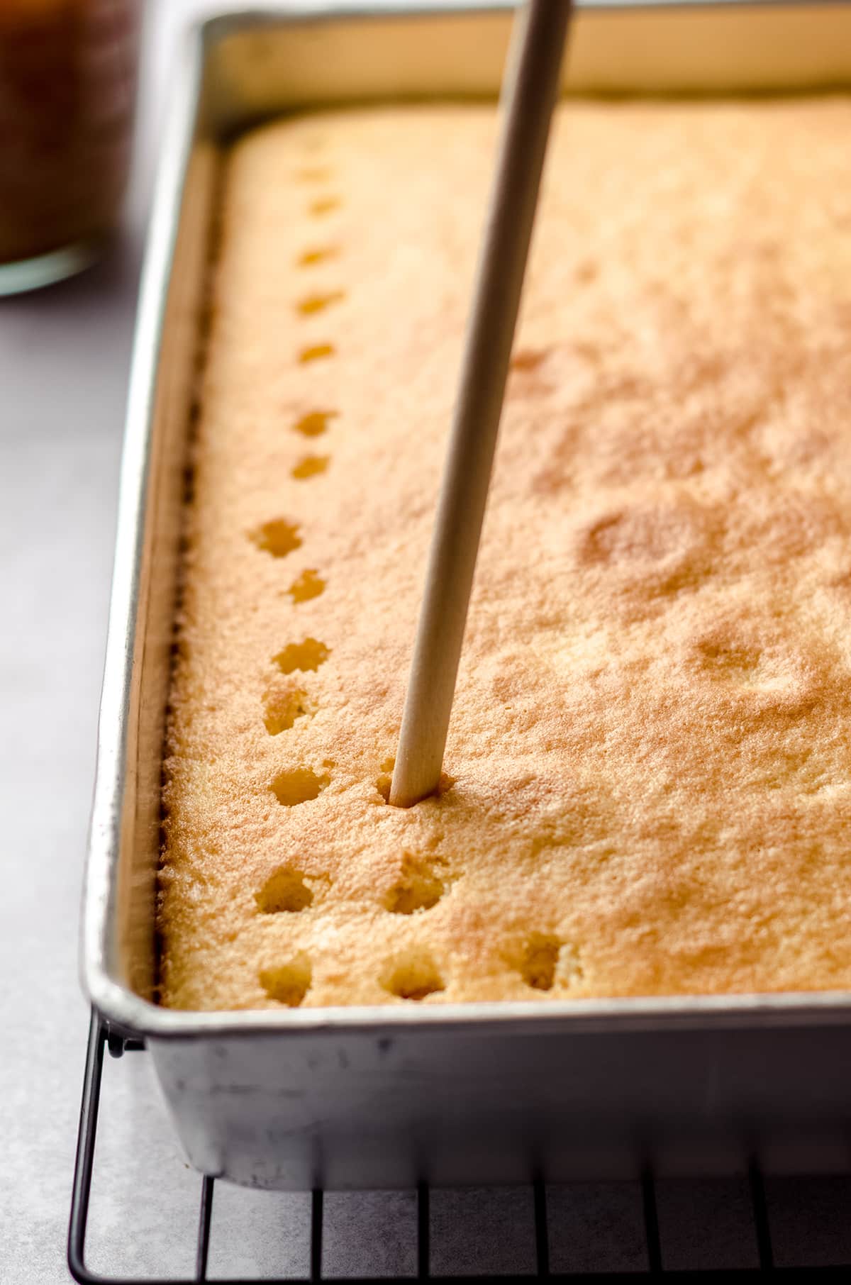 Poking holes in a cake that has been baked.