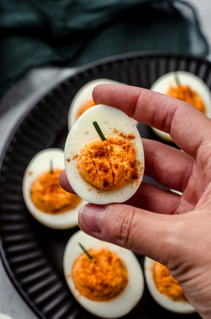 A picture of a hand holding a Halloween pumpkin deviled egg.