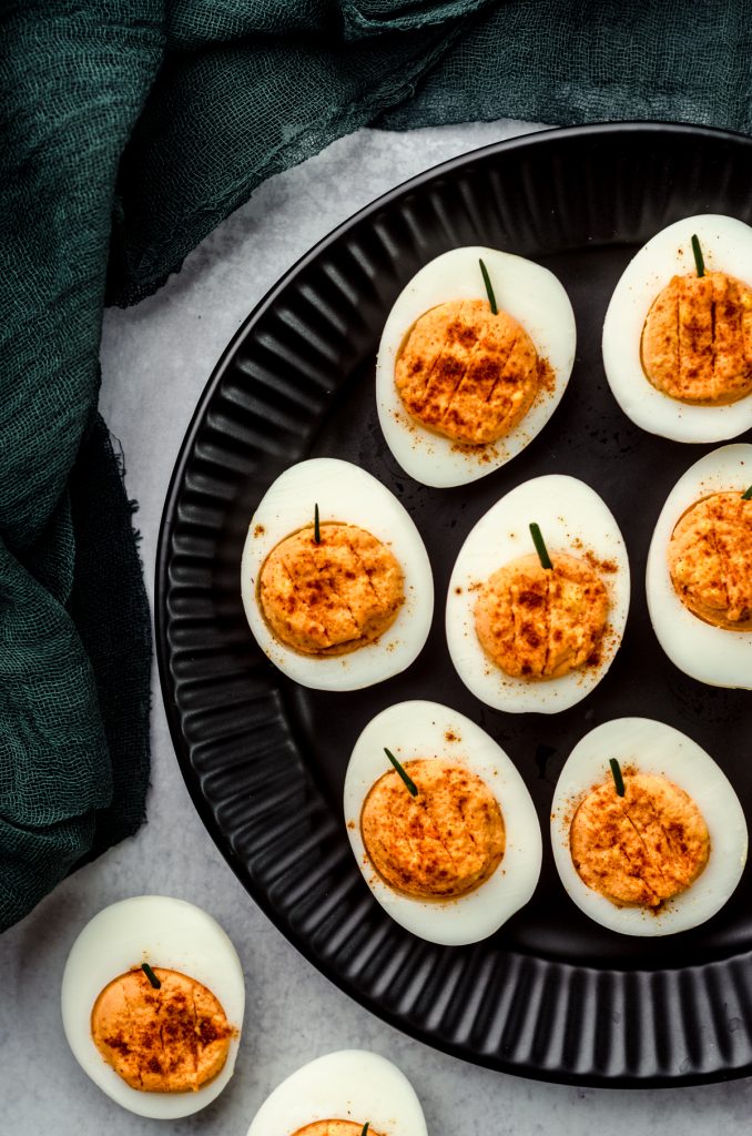 Halloween pumpkin deviled eggs on a black plate.