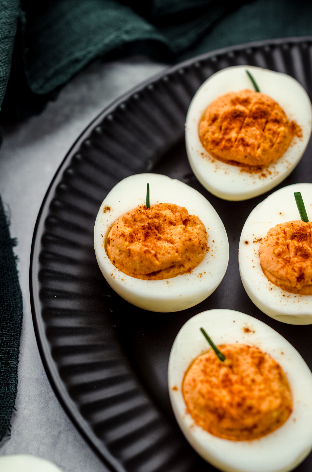 Halloween pumpkin deviled eggs on a black plate.