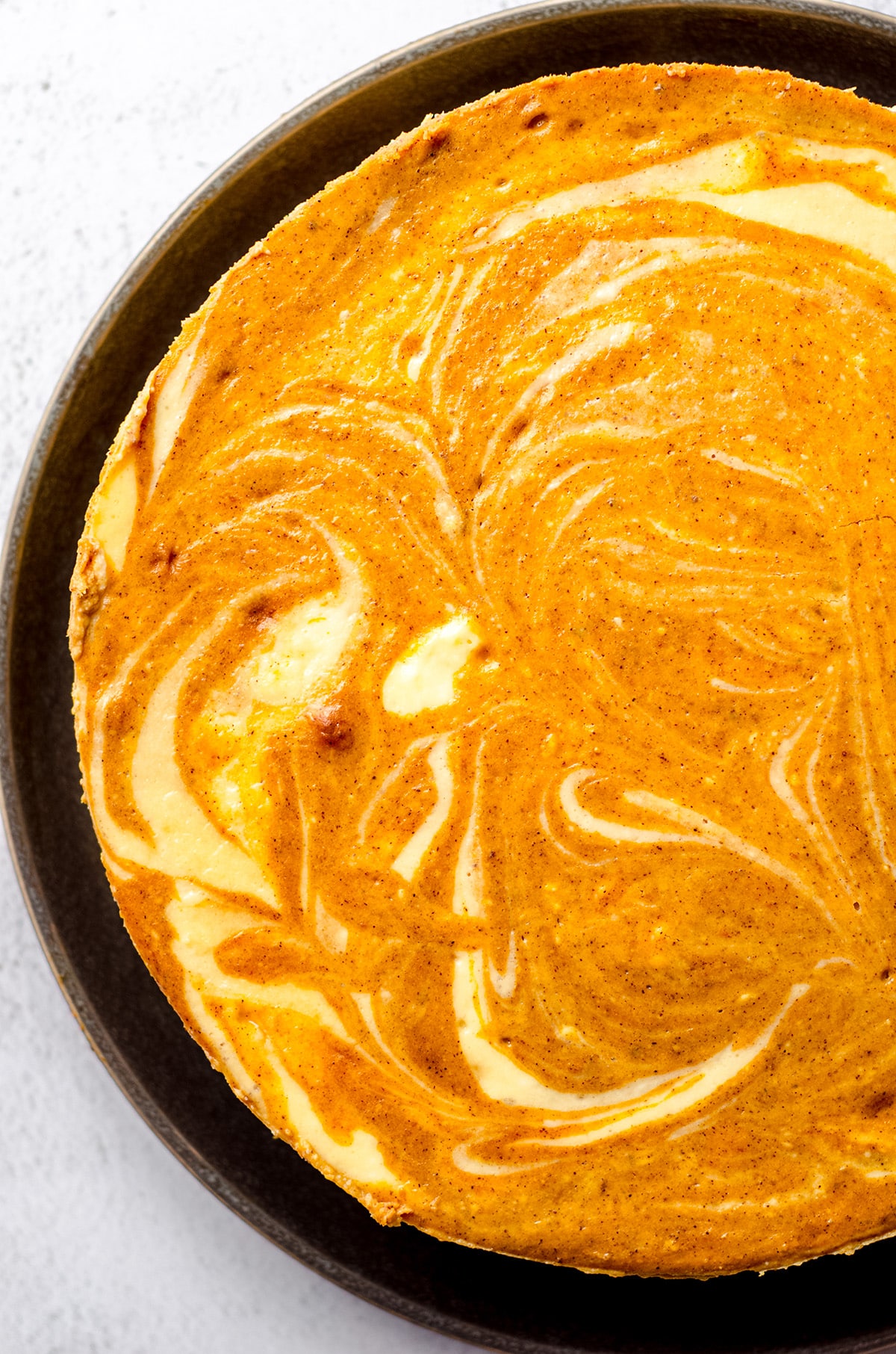 A baked pumpkin cheesecake with a swirl.