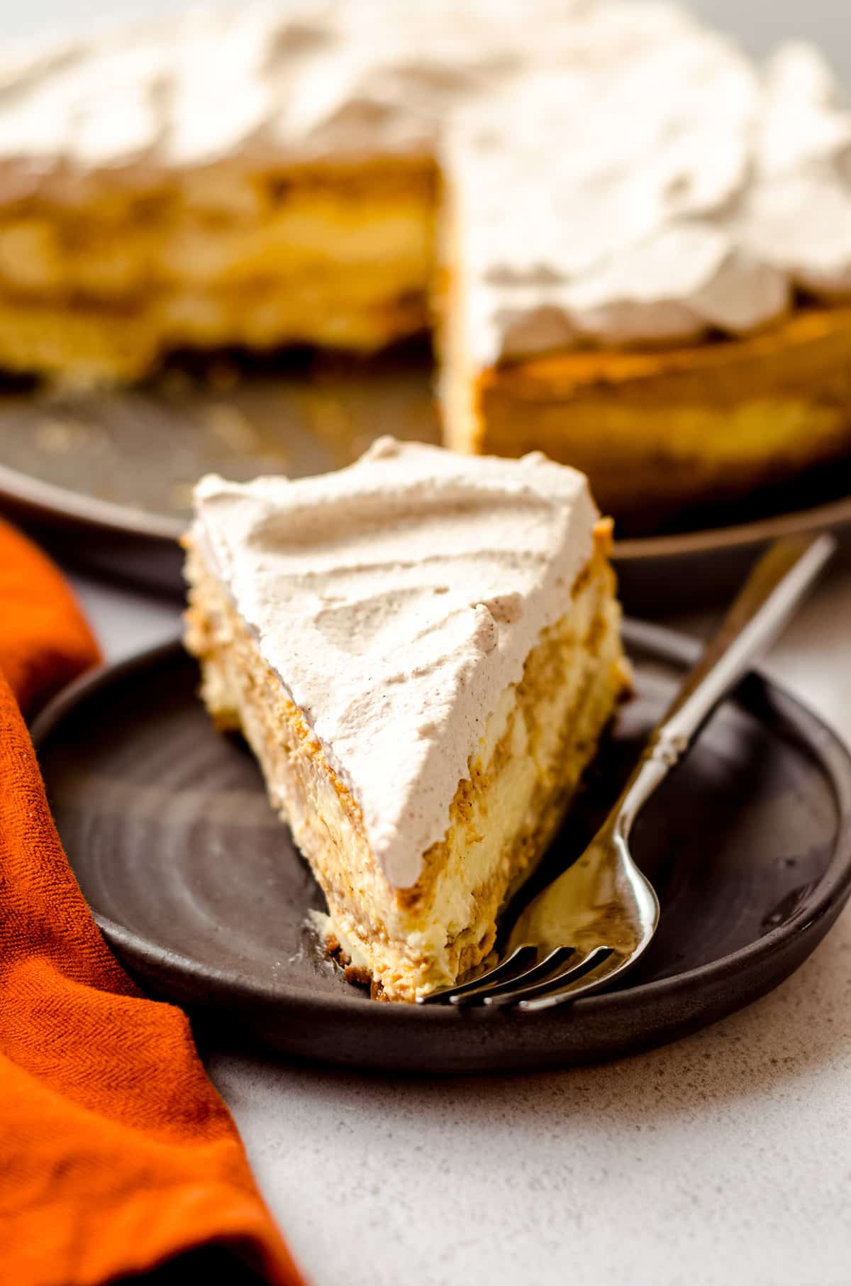 A slice of pumpkin cheesecake topped with whipped cream.
