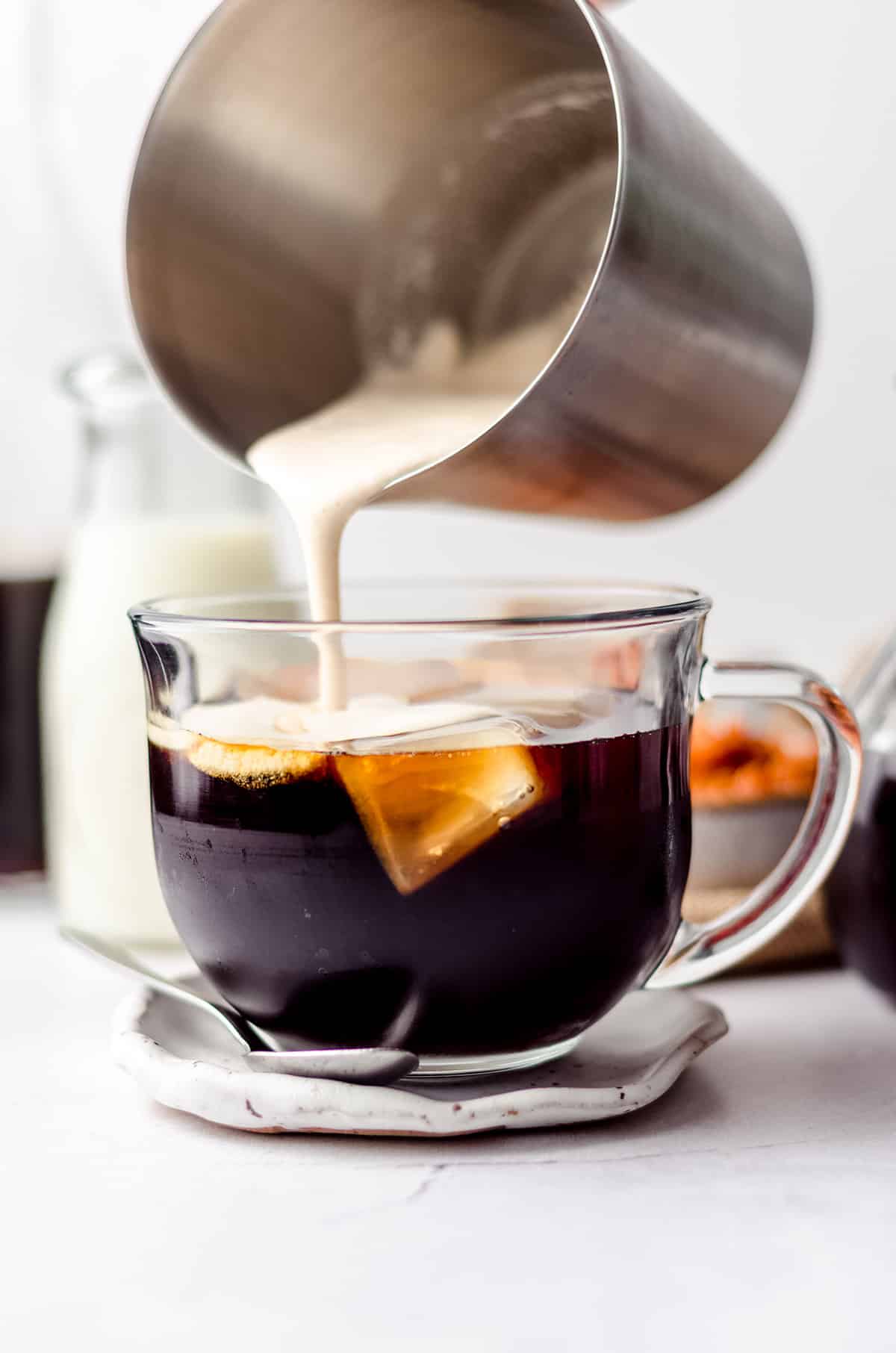 pouring pumpkin cold foam from a frother onto cold brewed coffee