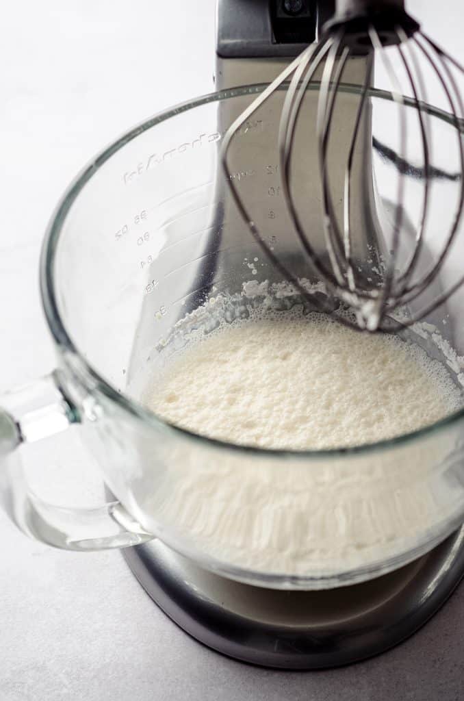 process photo of making whipped cream while it is in the bowl of a stand mixer