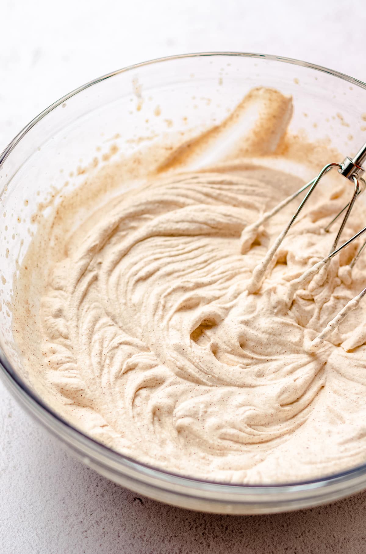 hand mixer beaters in a bowl of pumpkin spice whipped cream