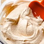 pumpkin spice whipped cream in a bowl spread around with an orange spatula