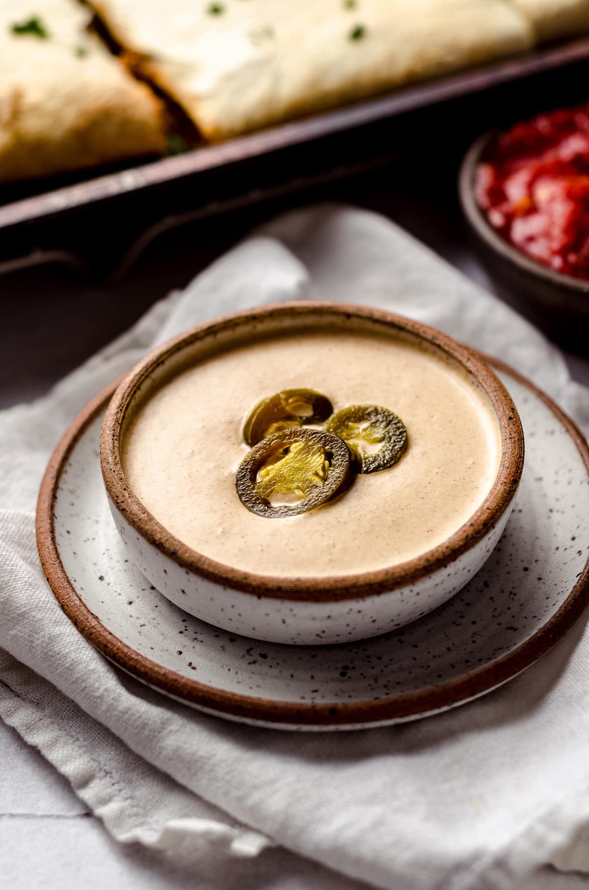 A bowl of quesadilla sauce topped with jalapeño rings.