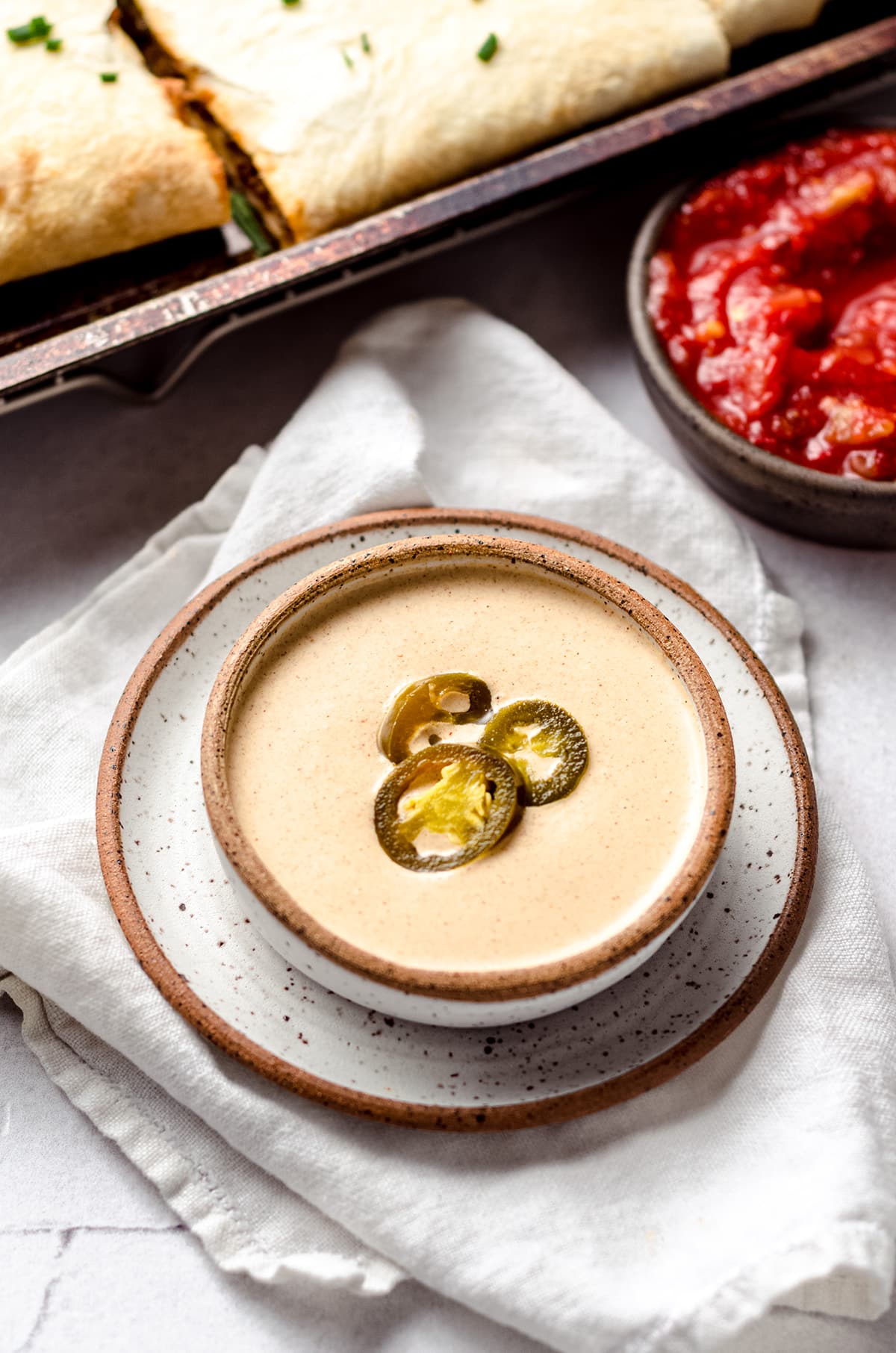 A bowl of quesadilla sauce topped with jalapeño rings.