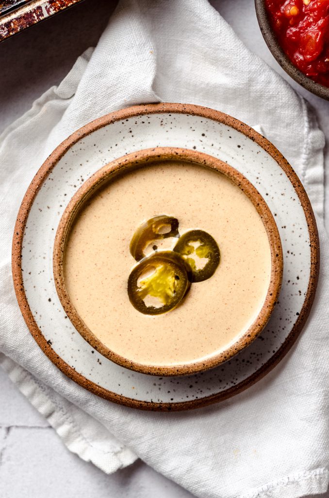 A bowl of quesadilla sauce topped with jalapeño rings.