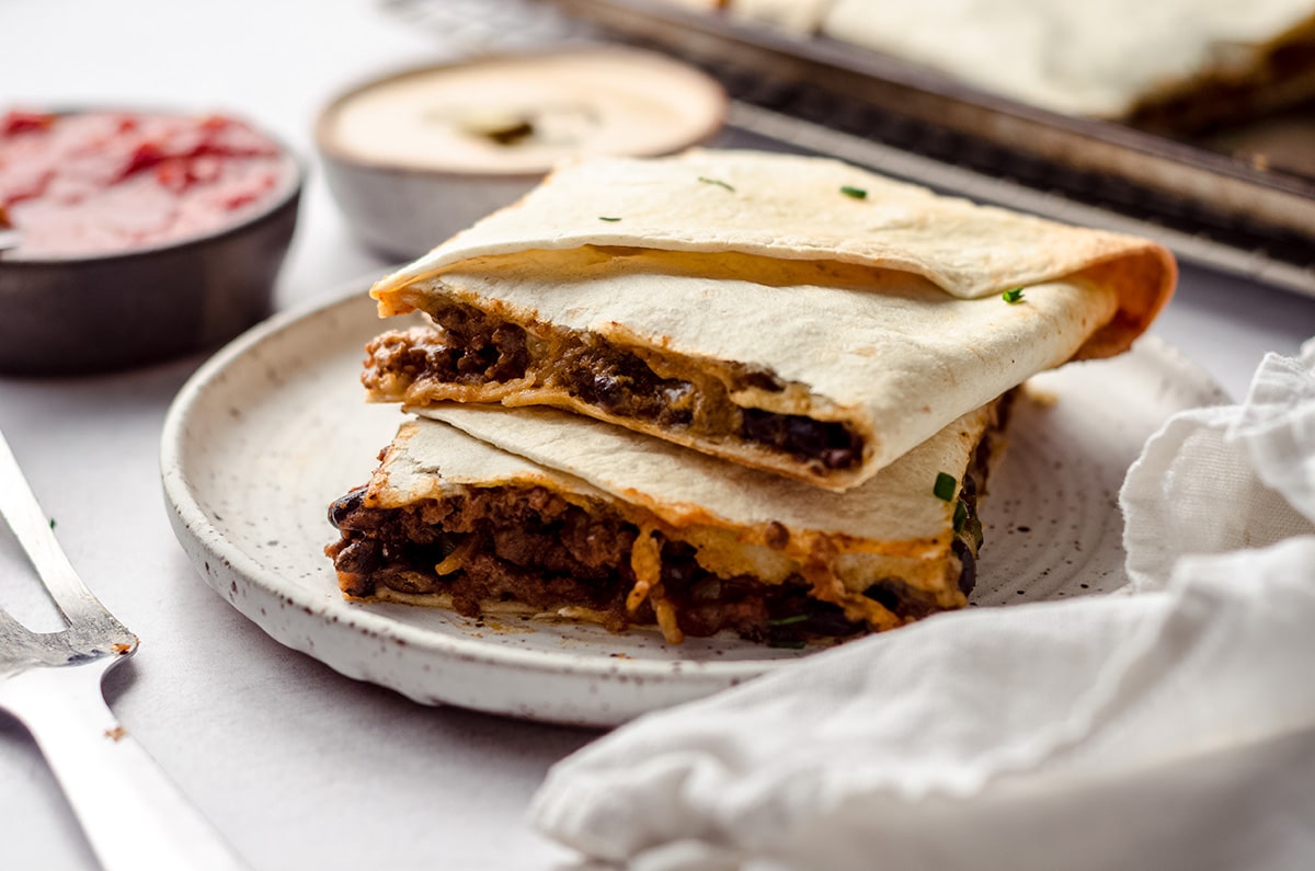 A stack of two square quesadillas on a plate.