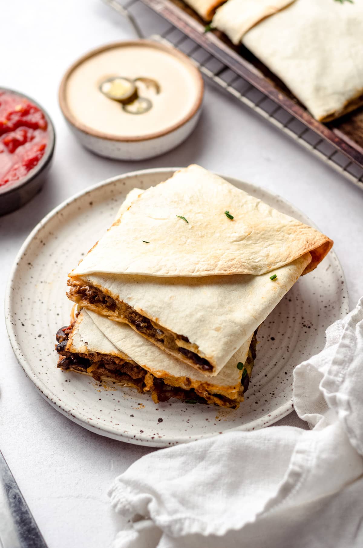 Two square tortilla wraps on a plate.