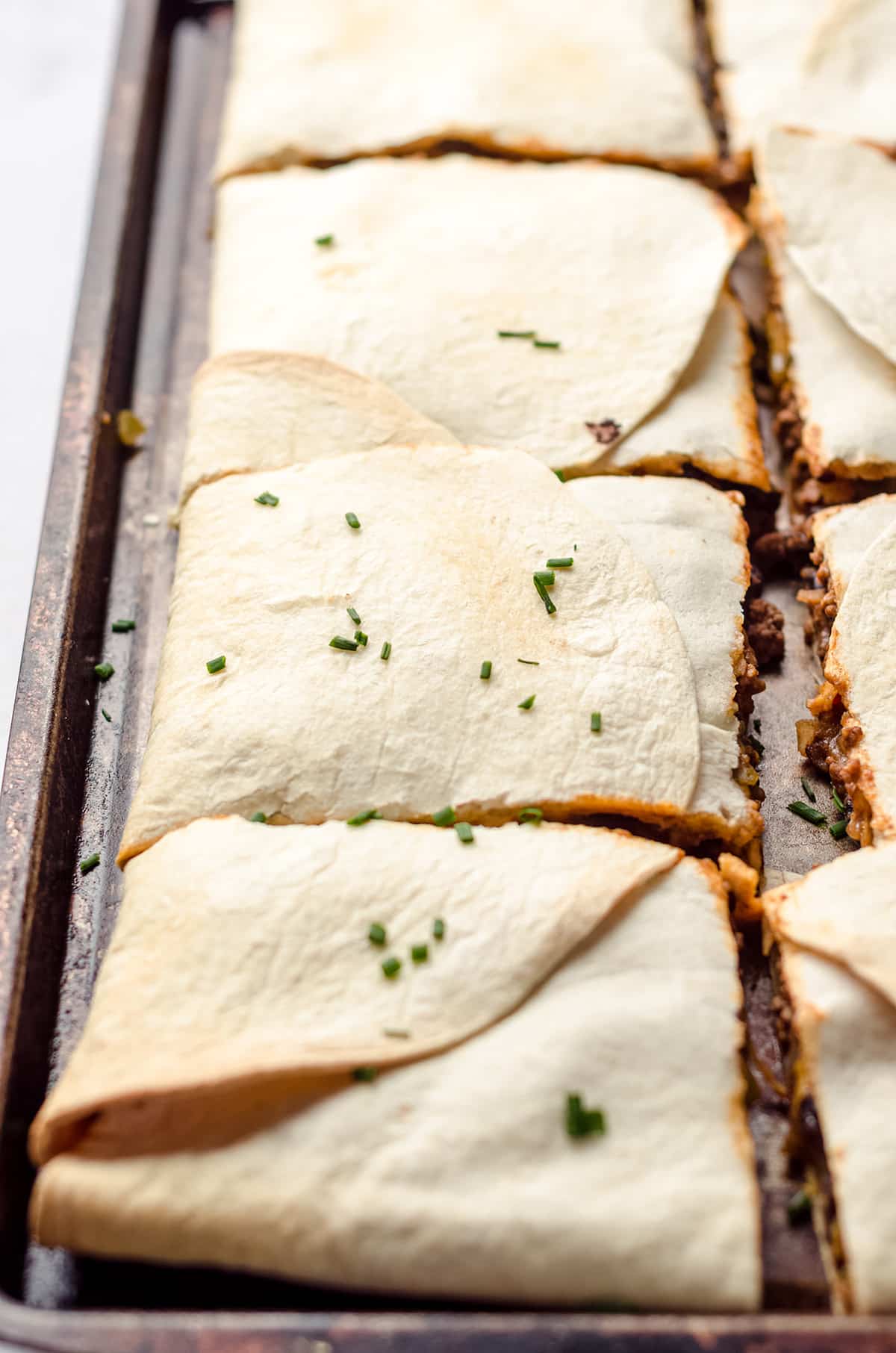 Quesadillas that have been baked on a sheet pan and cut into squares.