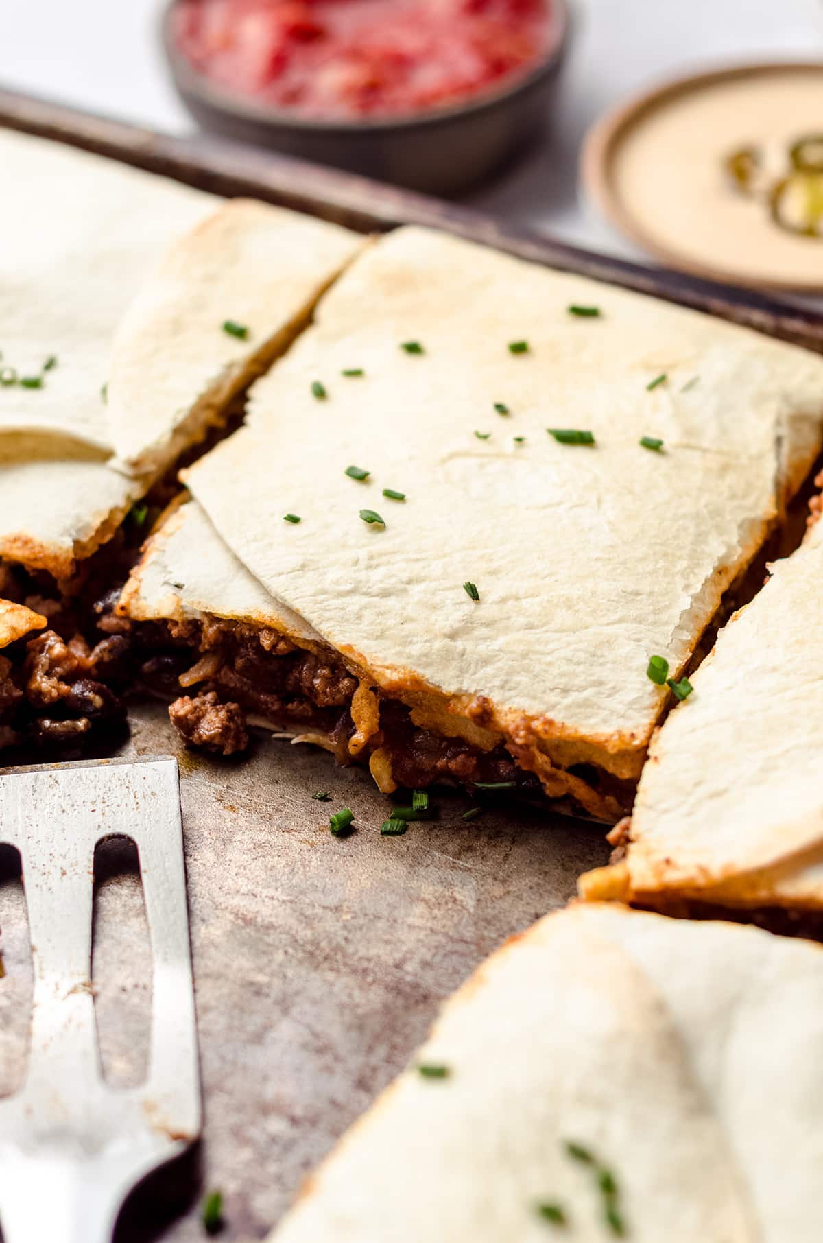 A close up of sheet pan quesadillas filled with ground beef and cheese.