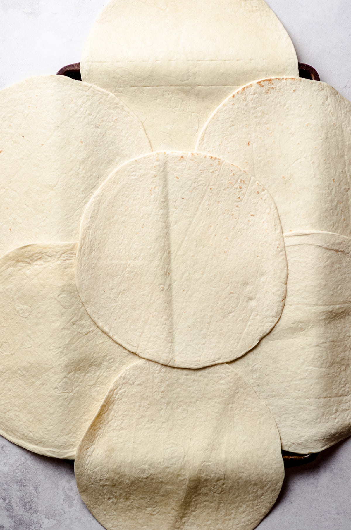 Layering tortillas on a sheet pan.