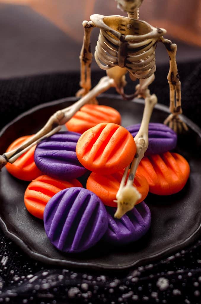 A plastic skeleton sitting on top homemade candies.
