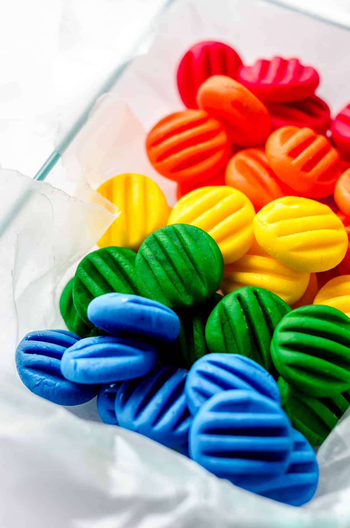 A parchment lined container with colorful homemade cream cheese mints.