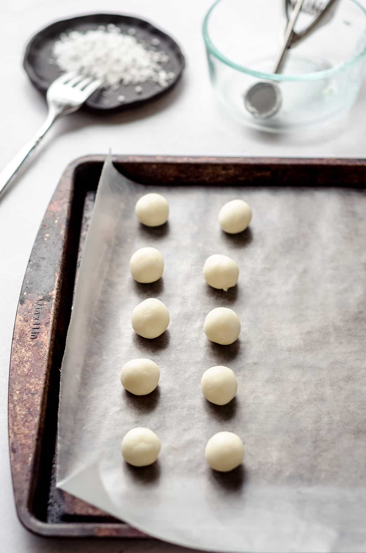 Small balls of cream cheese dough on a baking sheet.