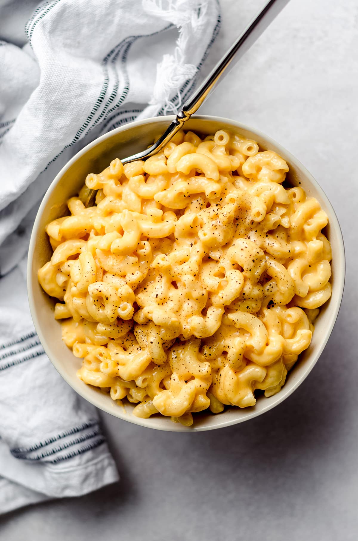 A bowl of macaroni and cheese, with a fork stuck into the side.