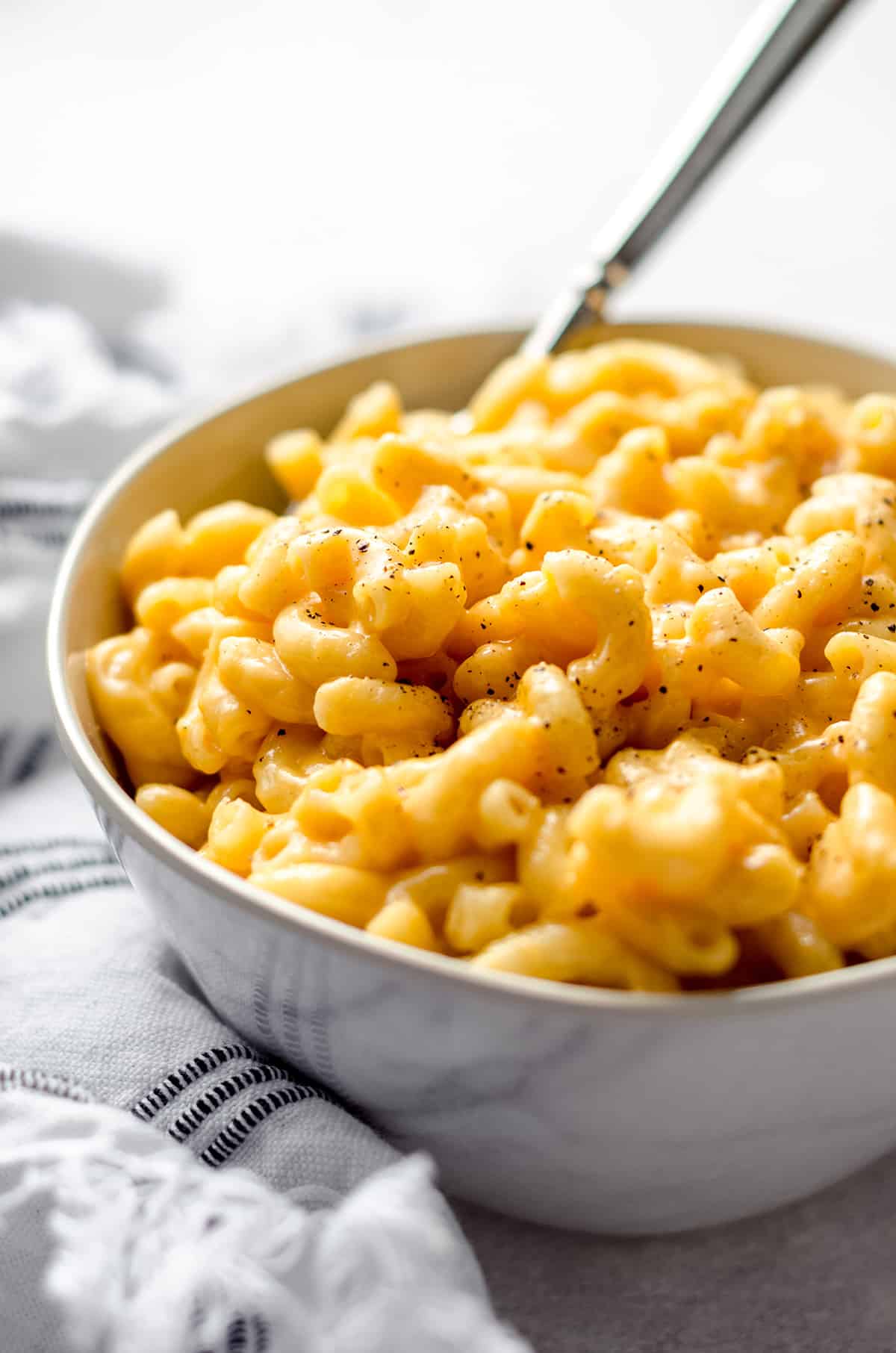 A bowl of macaroni and cheese with a fork sticking out.