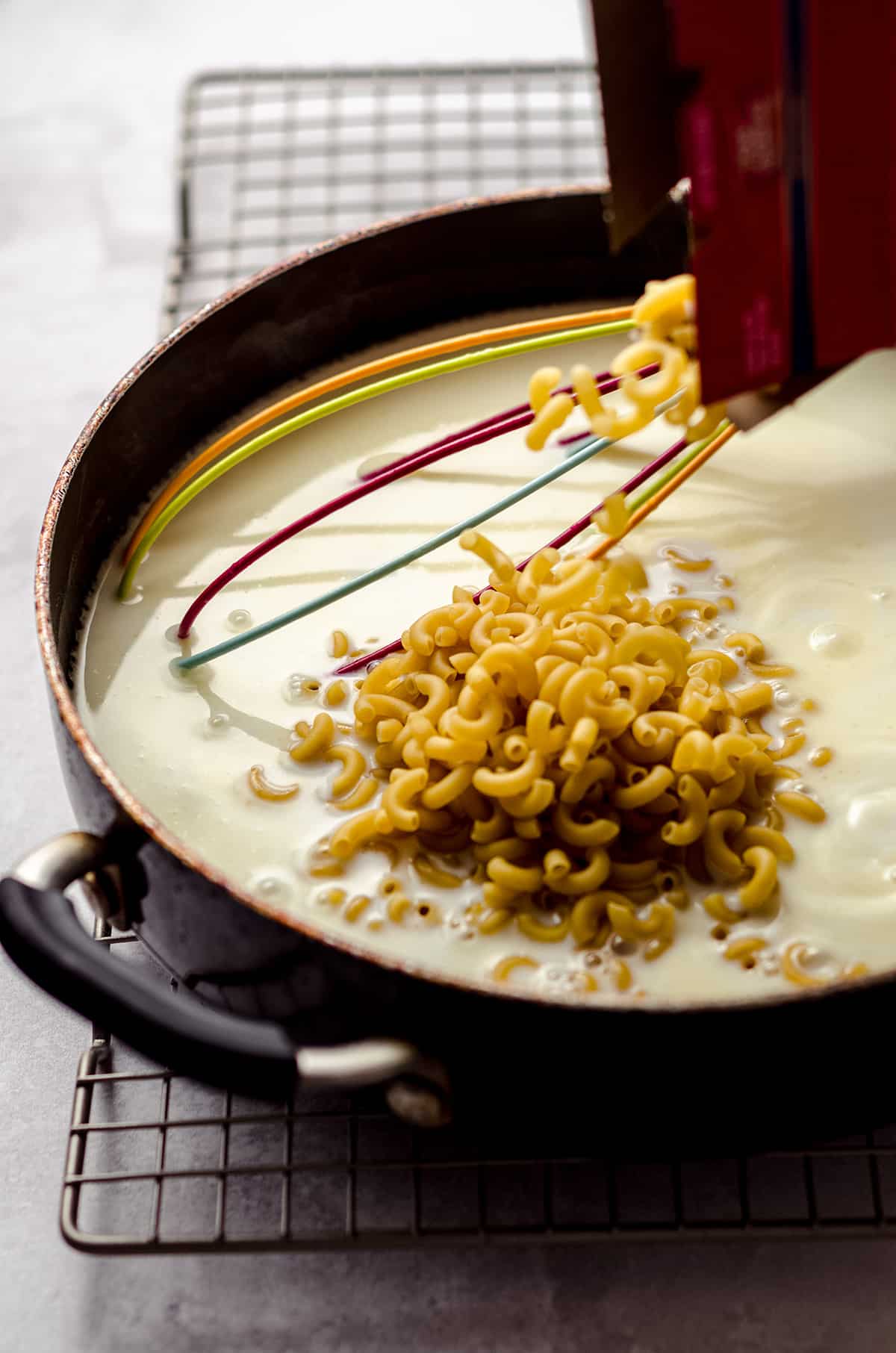 Adding macaroni into white sauce.