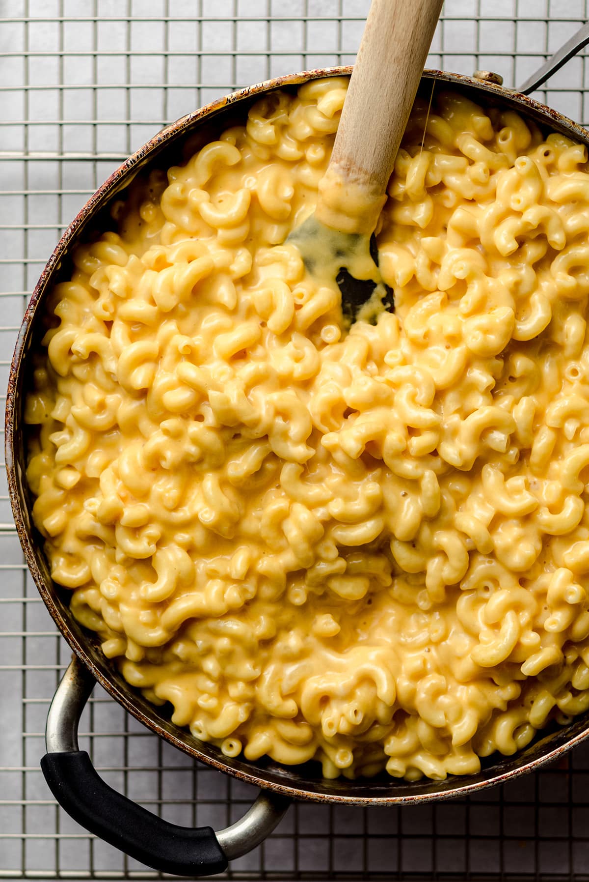A skillet filled with homemade Mac and cheese and a wooden spoon.