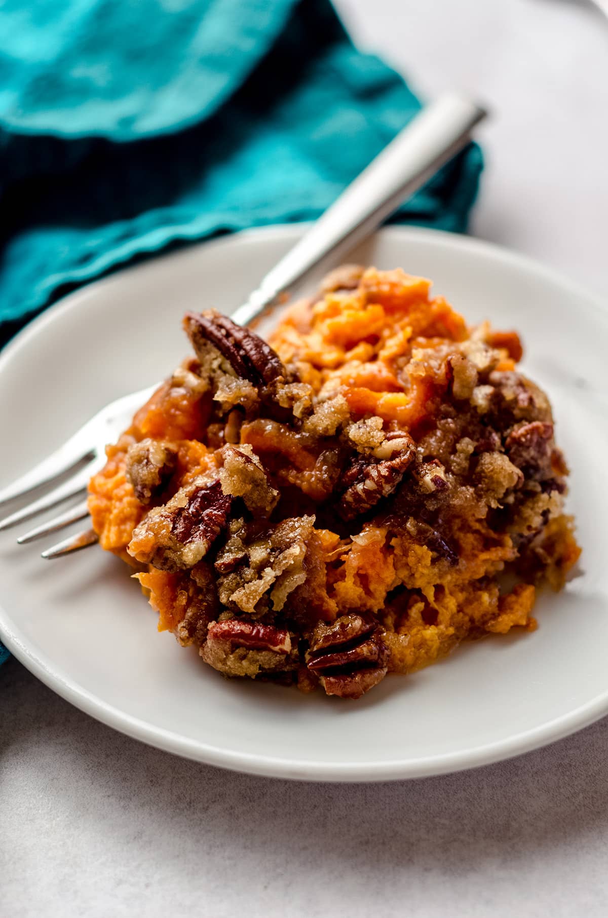 A scoop of sweet potato casserole on a white dish.