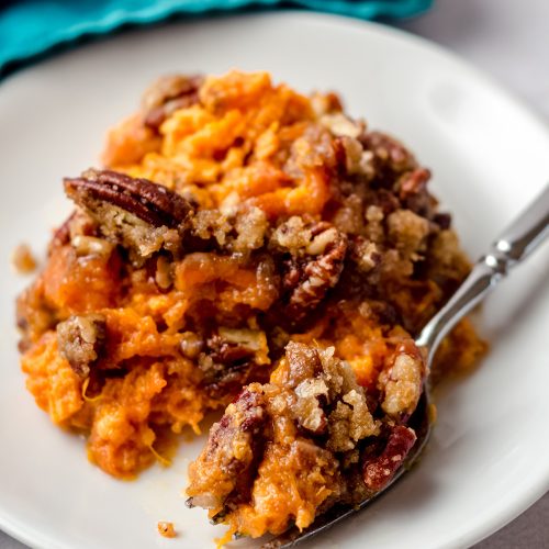 A fork taking a portion of sweet potato casserole.