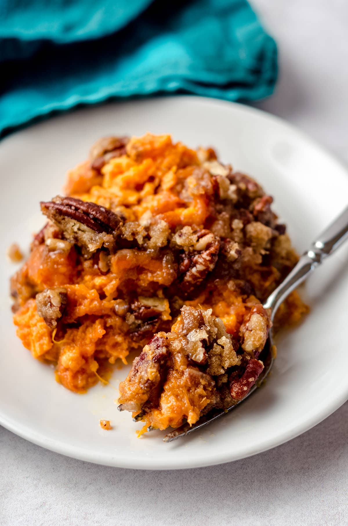 A fork taking a portion of sweet potato casserole.