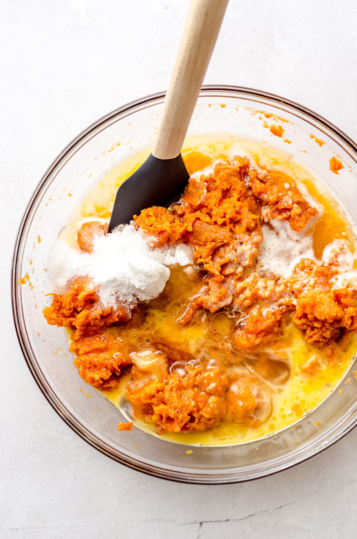 Adding melted butter, brown sugar, and other ingredients to mashed sweet potato.