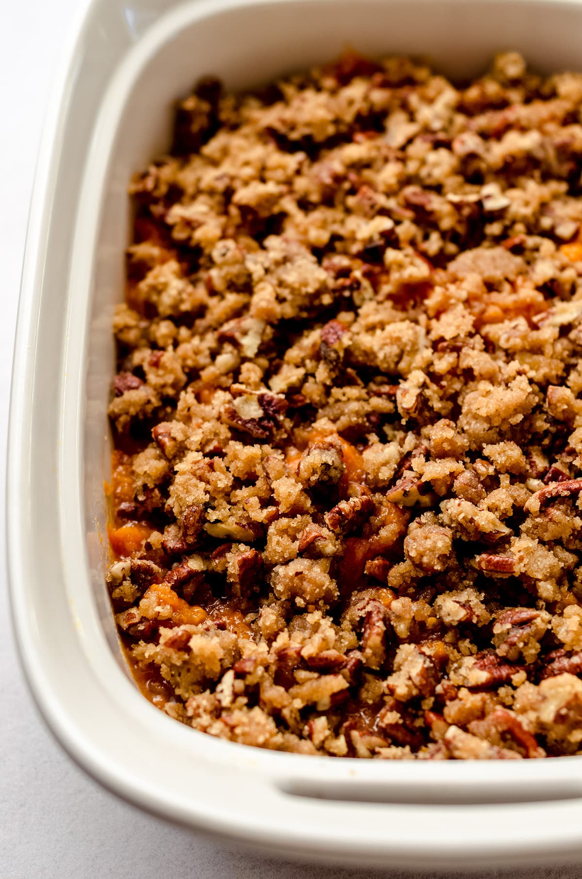 A baking dish full of sweet potato casserole, topped with pecans.