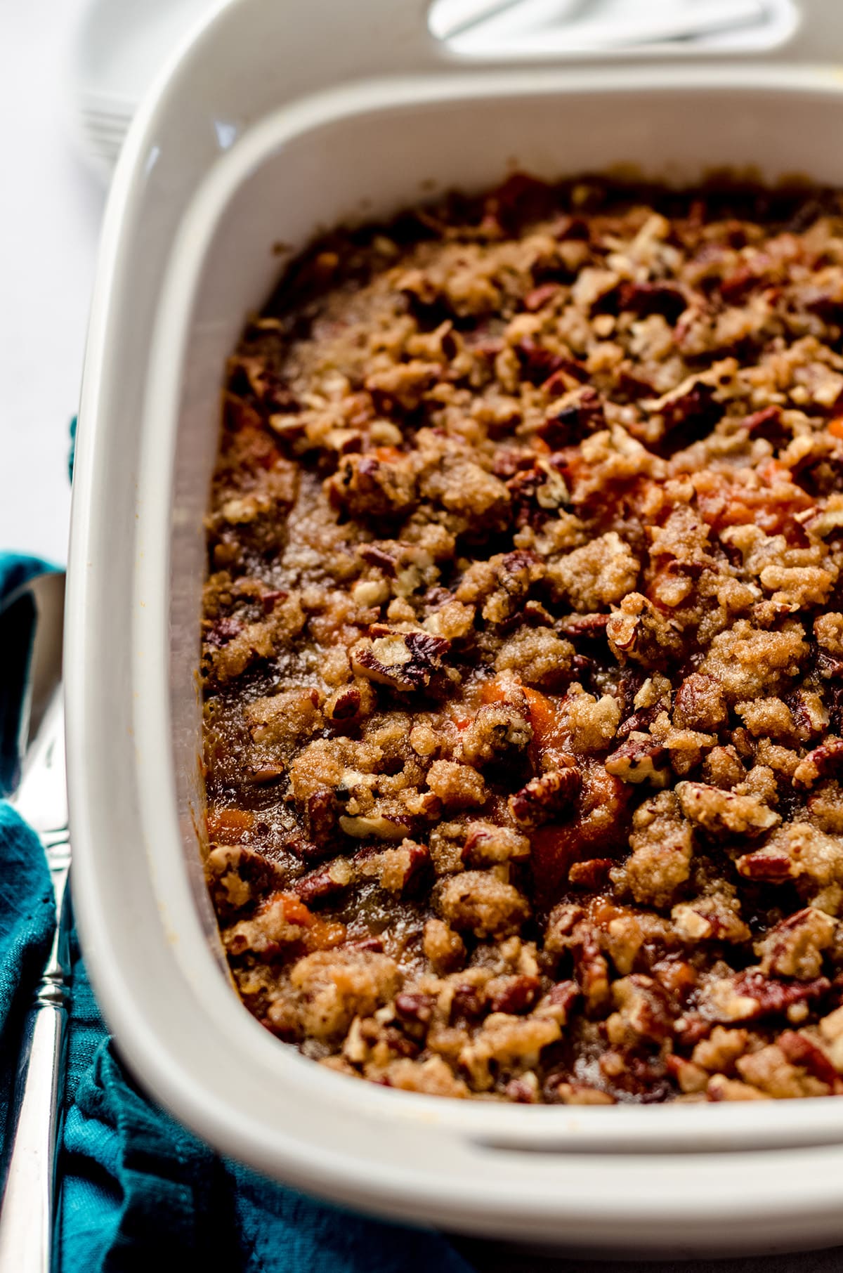 A baking dish filled with sweet potato casserole and topped with pecans.