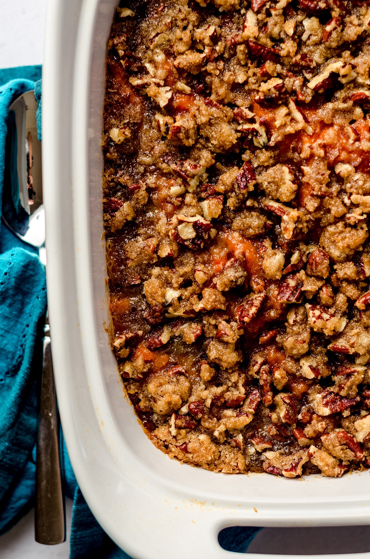 A casserole dish with sweet potatoes with a pecan topping.