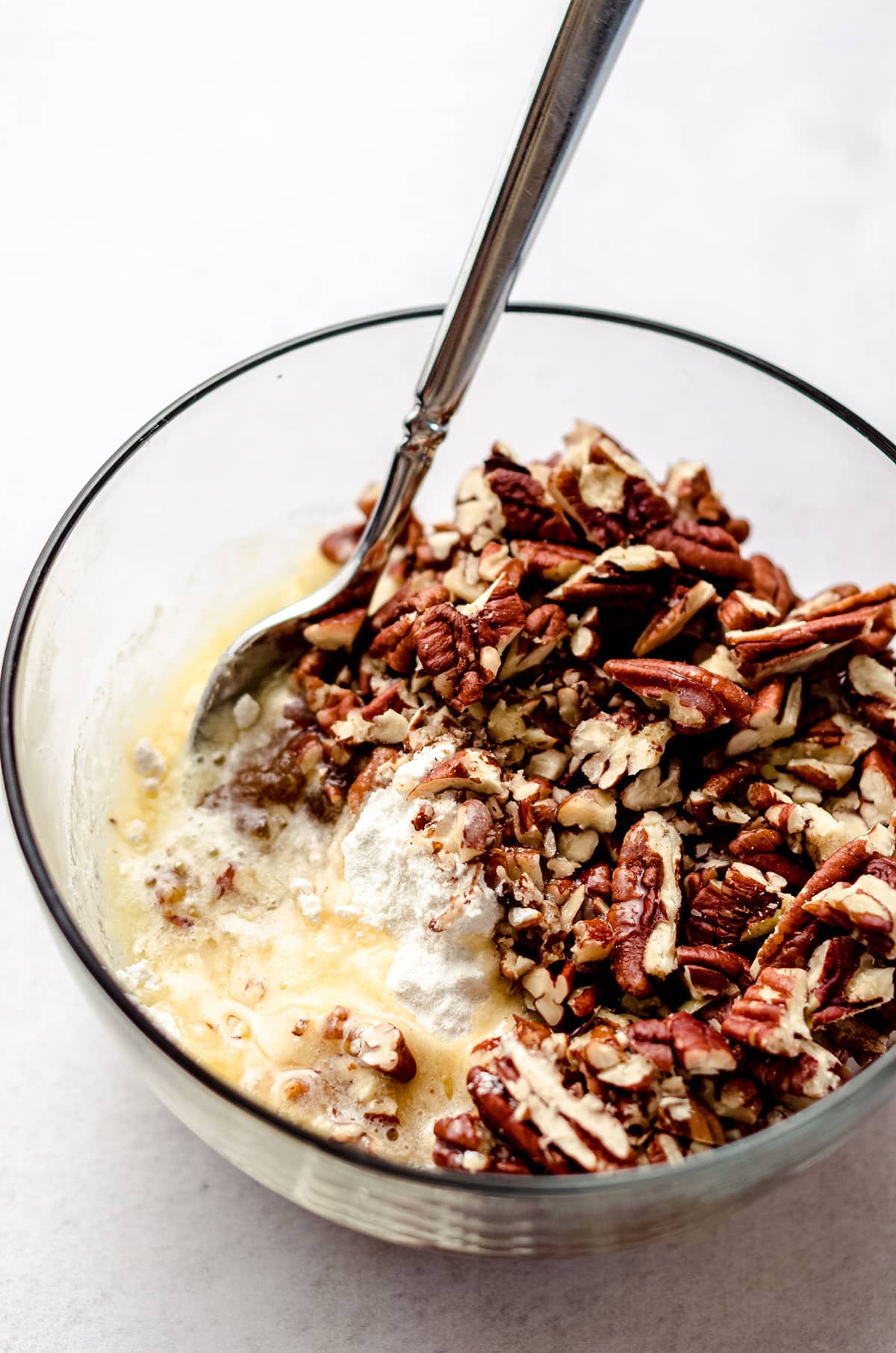 A bowl of chopped pecans with melted butter.