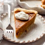 A slice of sweet potato pie, topped with whipped cream.