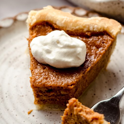 A slice of sweet potato pie topped with whipped cream.