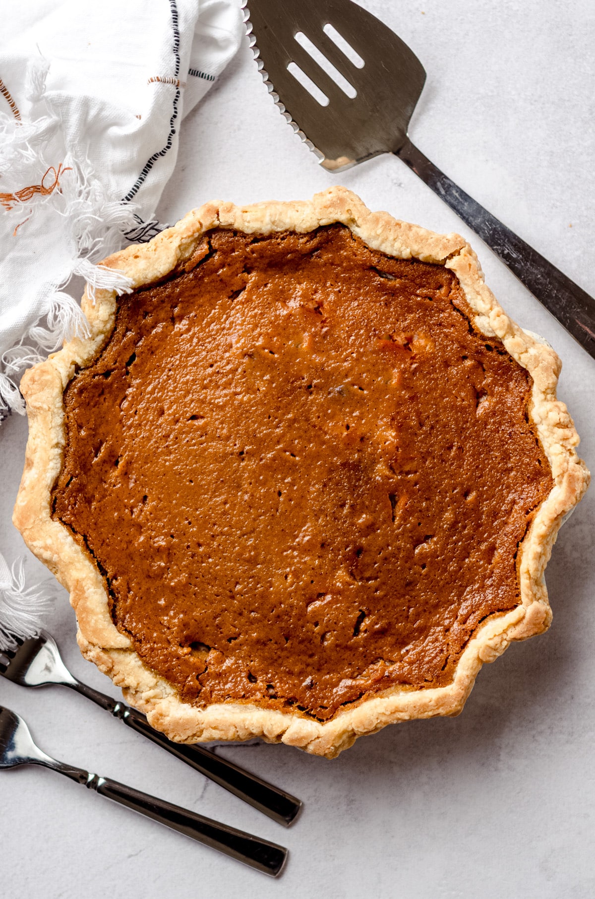 A sweet potato pie on a counter, with a serving spatula on the side.