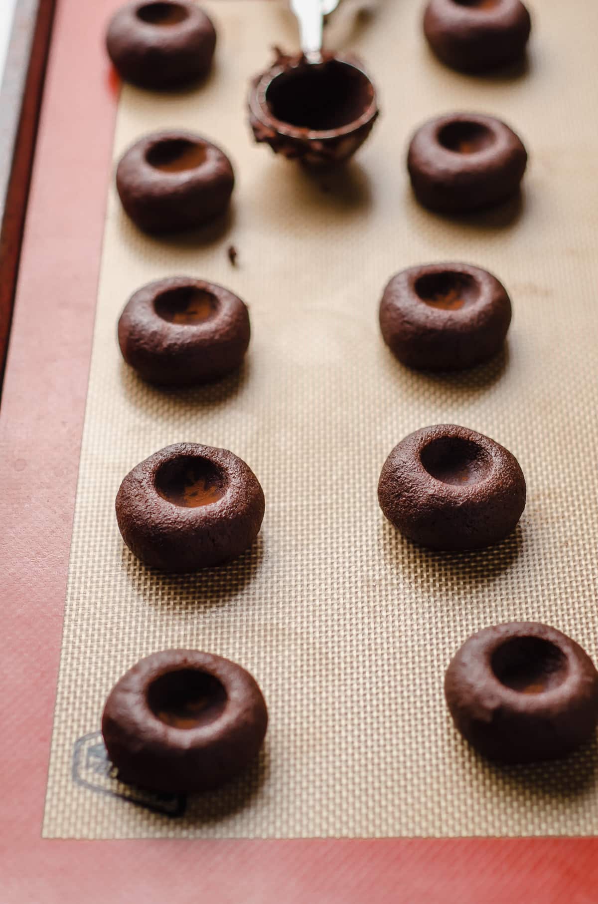 chocolate thumbprint cookies on a baking sheet ready to be baked