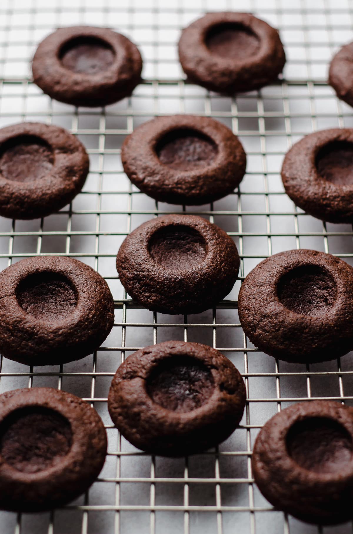 chocolate thumbprint cookies on a cooling rack ready to be filled