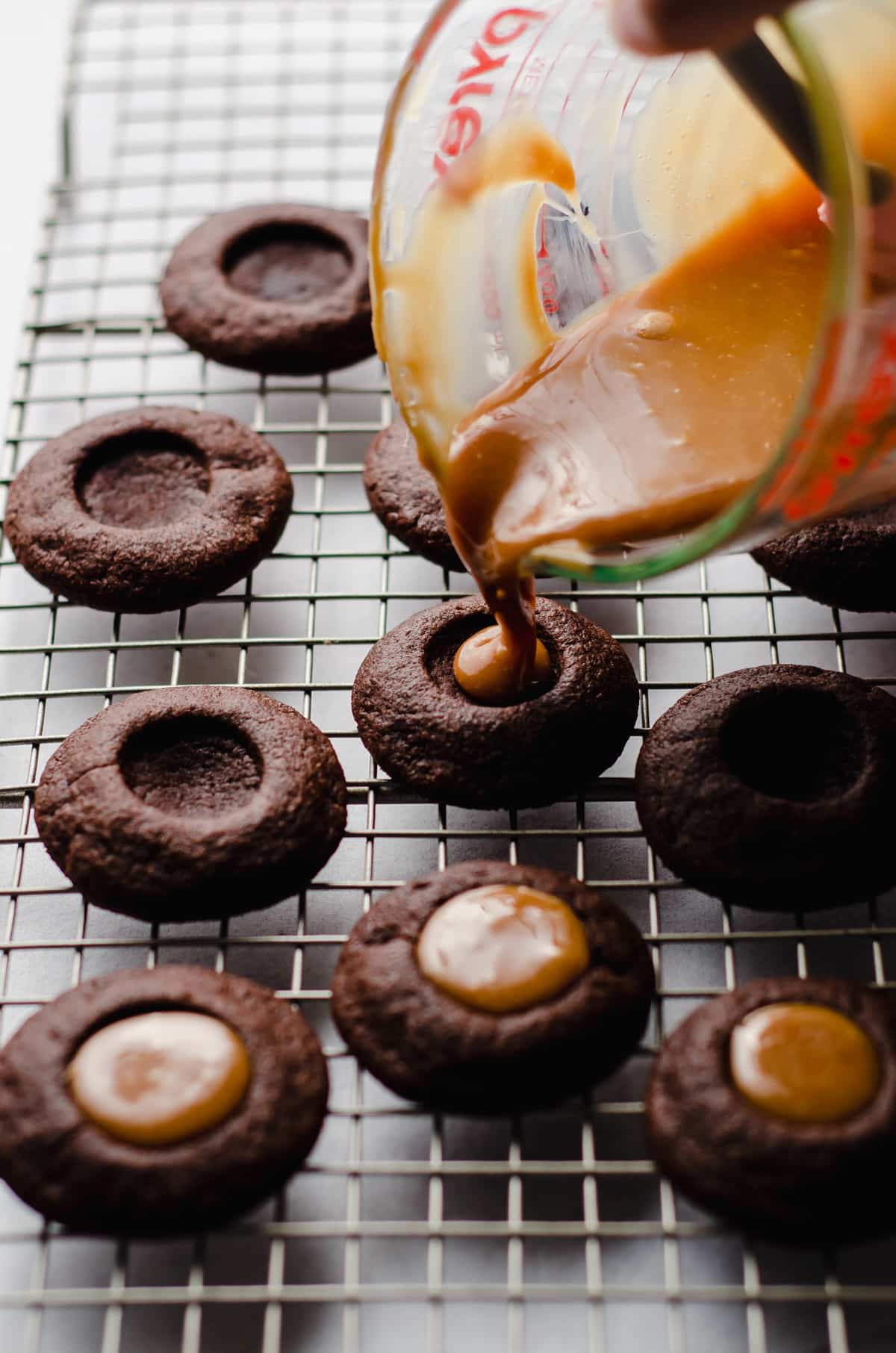 pouring caramel into chocolate thumbprint cookies
