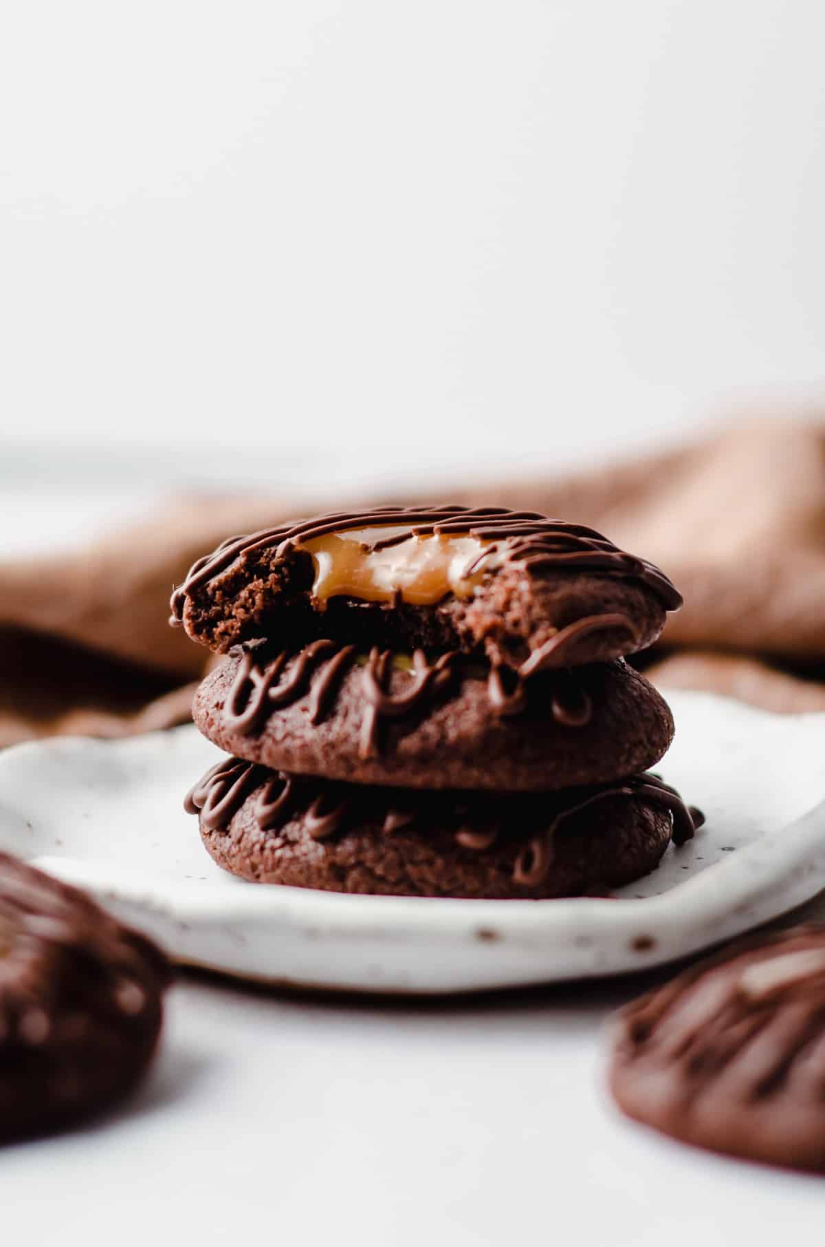 stack of salted caramel chocolate thumbprint cookies with a bite taken out of the one on the top