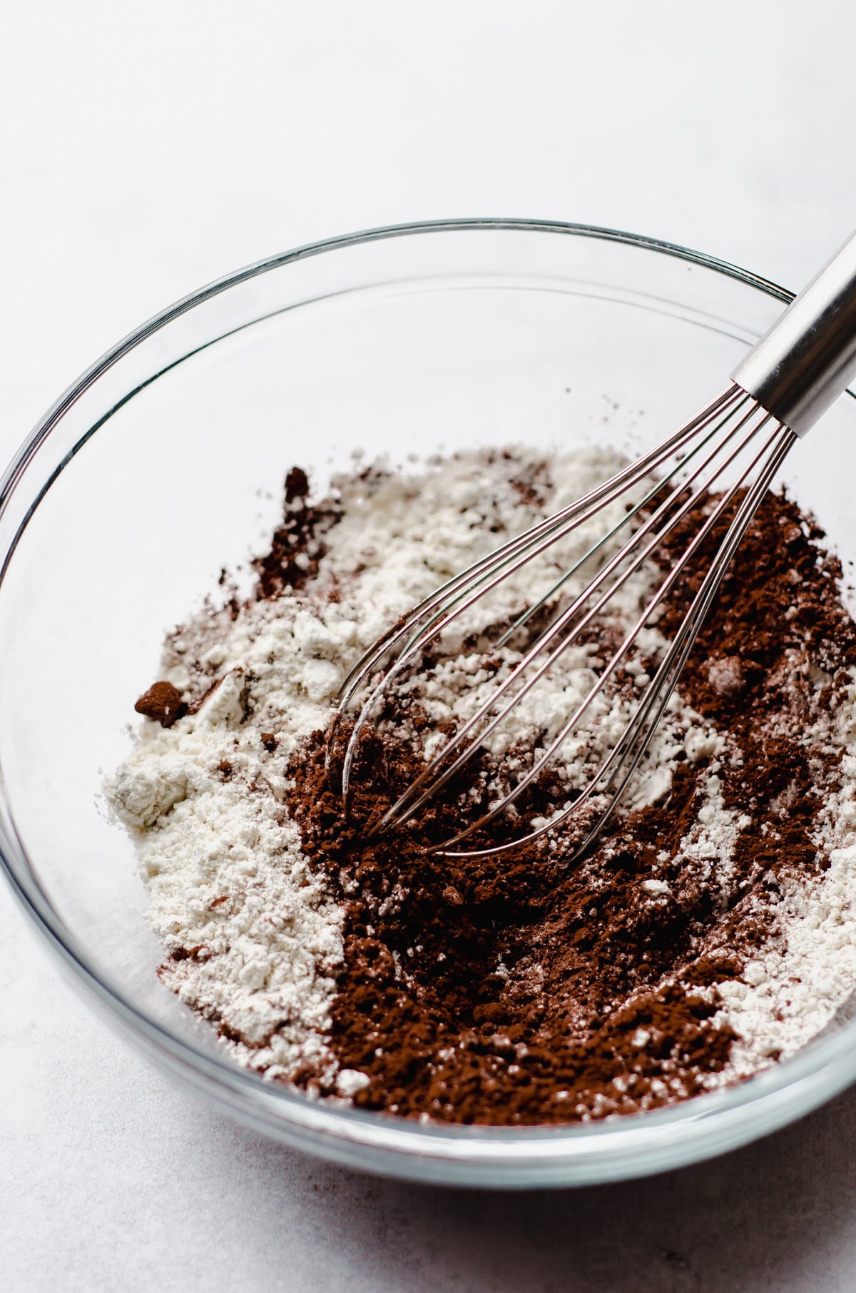 flour and cocoa powder in a glass bowl with a whisk