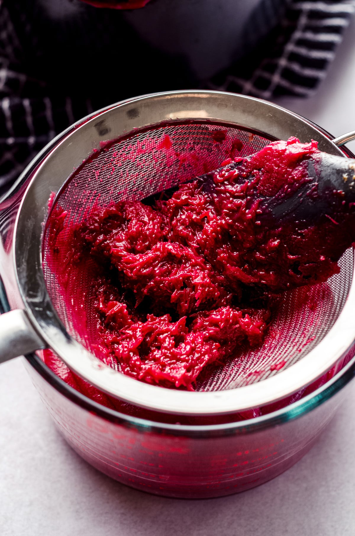 cranberry pulp in a strainer with a spatula